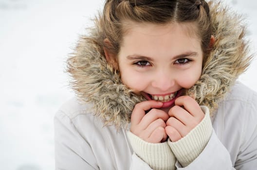 Portrait of smiling young girl in winter jacket with fur.