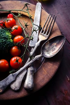 Old silverware and vegetable in wooden plate