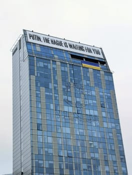 Vilnius, Lithuania: - 2022.03.07: Putin, The Hague is waiting for you inscription on the building of the Vilnius City Hall and the Ukrainian flag. THE UN Court in The Hague began consideration of the claim of Ukraine against Russia.