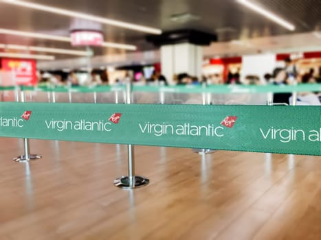 London, UK, July 2019: Green belt barrier with white Virgin Atlantic airlines logo. Virgin Atlantic is a British airline. Travel and airport security
