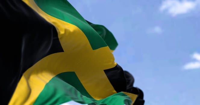Detail of the national flag of Jamaica waving in the wind on a clear day. Jamaica is an island country situated in the Caribbean Sea. Selective focus.
