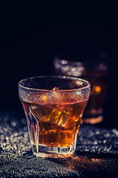 Two glass of iced cocktail on wet background. Vintage filter.