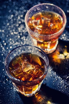 Two glass of iced cocktail on wet background