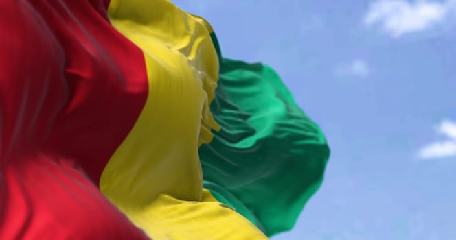 Detail of the national flag of Guinea waving in the wind on a clear day. Guinea is a coastal country in West Africa. Selective focus.