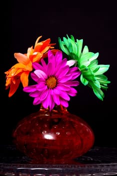 Pink orange and green Floral arrangement in a brown vase isolated over a black background
