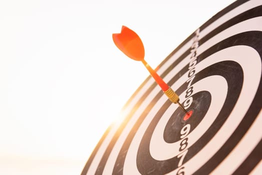 Closeup the dart arrow hit center on Bullseye(bull's-eye) of a dartboard is a target of challenge business, strategy marketing target, objective financial and goal a concept