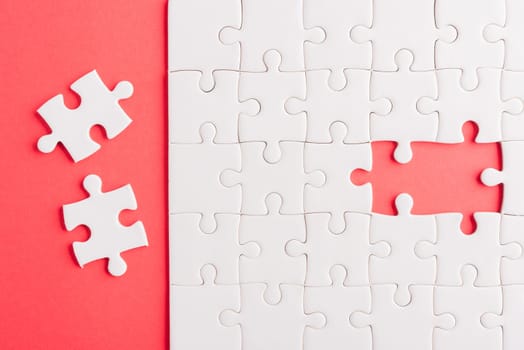 Top view flat lay of paper plain white jigsaw puzzle game texture last pieces for solve and place, studio shot on a red background, quiz calculation concept