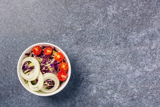 Top view of the healthy colorful salad bowl with tomatoes fresh mixed leaves vegetable in a dish on cement stone table background, Health salad snack diet food weight loss concept