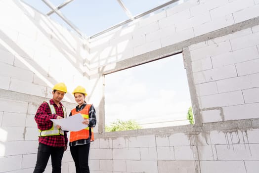 Architect and client discussing the plan with blueprint of the building at construction site. Asian engineer foreman worker man and woman working talking and checking on draw paper to checking project