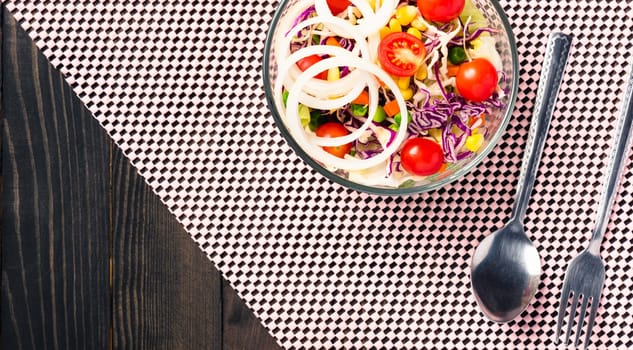 Top view of the healthy colorful fresh salad bowl with quinoa, tomatoes, and mixed greens vegetable in a dish on black wooden background, Health snack food