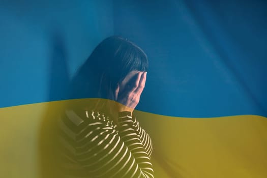 War between Russia and Ukraine. Woman with sad sight over Ukraine flag.