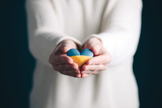 Heart shaped flag of Ukraine in female hands. The concept of solidarity with the citizens of Ukraine.