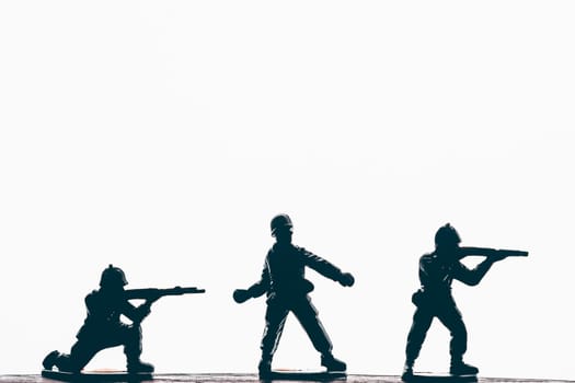 Silhouette of male soldiers wearing army, uniform and helmet. Man holding weapon machine in hands. White studio background.