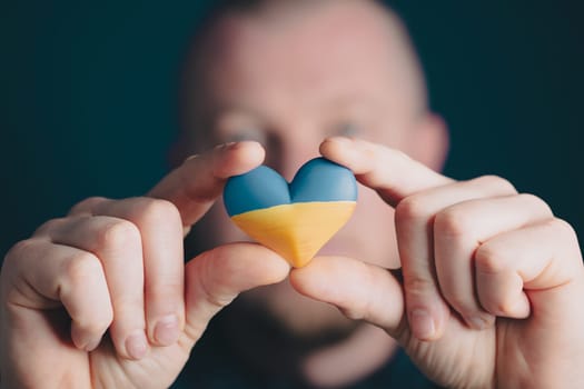 Heart shaped flag of Ukraine in male hands. The concept of solidarity with the citizens of Ukraine.
