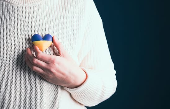 Heart shaped flag of Ukraine in female hands. The concept of solidarity with the citizens of Ukraine.