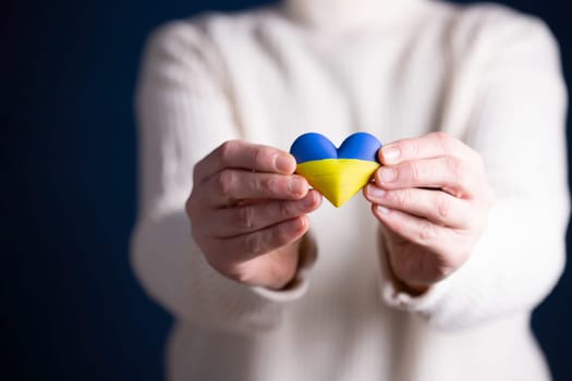 Heart shaped flag of Ukraine in female hands. The concept of solidarity with the citizens of Ukraine.