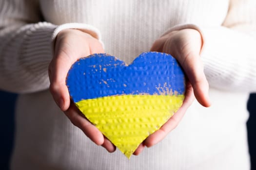 Heart shaped flag of Ukraine in female hands. The concept of solidarity with the citizens of Ukraine.