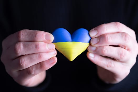 Heart shaped flag of Ukraine in female hands. The concept of solidarity with the citizens of Ukraine.