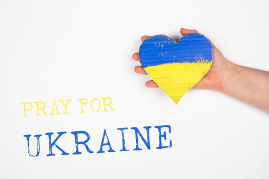Heart shaped flag of Ukraine in female hands, Pray for Ukraine text.  The concept of solidarity with the citizens of Ukraine.