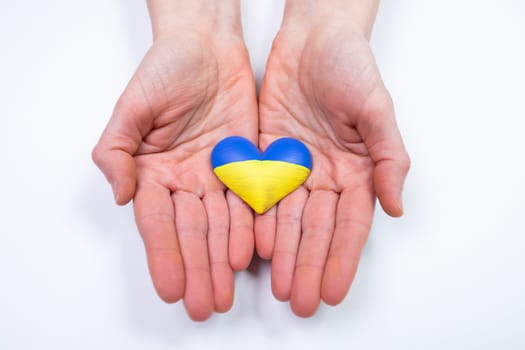 Heart shaped flag of Ukraine in female hands. The concept of solidarity with the citizens of Ukraine.