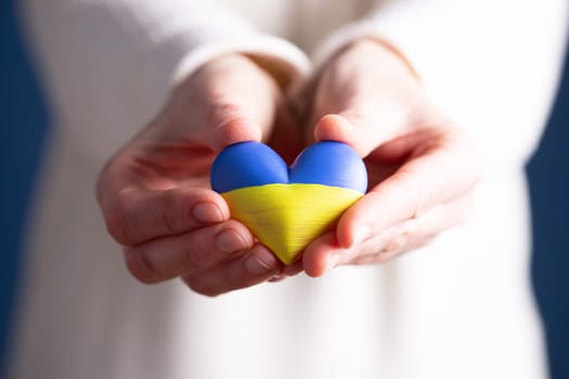 Heart shaped flag of Ukraine in female hands. The concept of solidarity with the citizens of Ukraine.