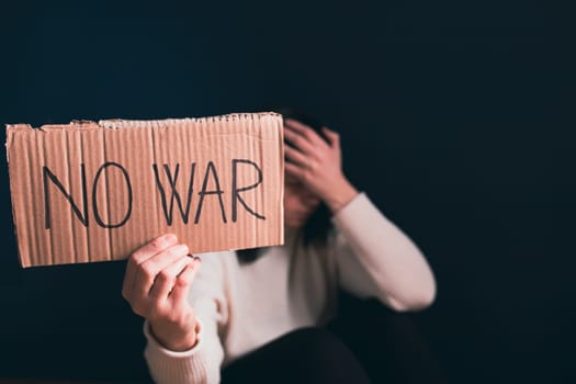 Sad woman calls to Stop war in Ukraine, raises banner with inscription No war.