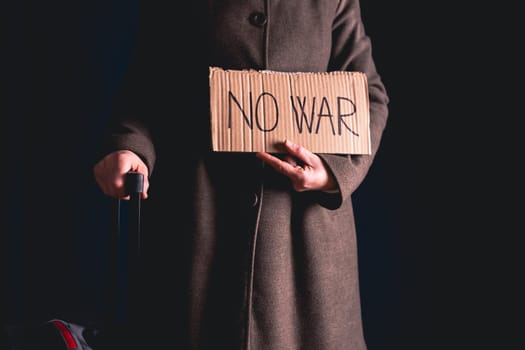 Ukrainian refugee holding placard with No war text. Evacuation of civilians. Freedom to Ukraine concept.