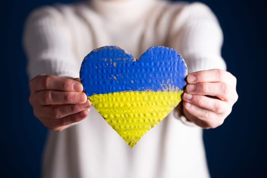 Heart shaped flag of Ukraine in female hands. The concept of solidarity with the citizens of Ukraine.