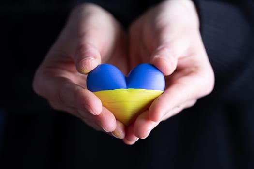 Heart shaped flag of Ukraine in female hands. The concept of solidarity with the citizens of Ukraine.
