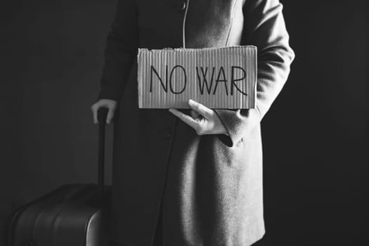 Ukrainian refugee holding placard with No war text. Evacuation of civilians. Freedom to Ukraine concept.