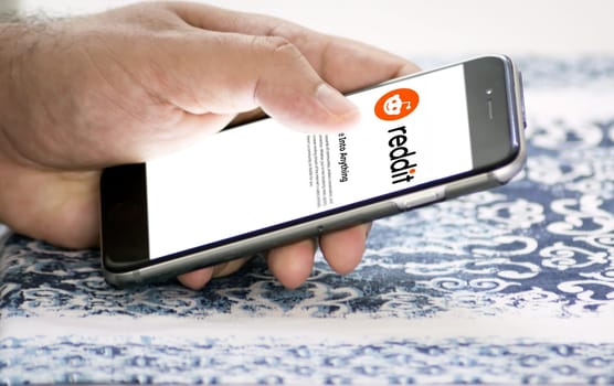 Rome, Italy, January 2022: Hand holding a smart phone with Reddit mobile app on the screen. Reddit is an American social news aggregation and discussion website application