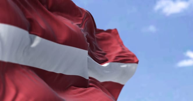 Detail of the national flag of Latvia waving in the wind on a clear day. Latvia is a country in the Baltic region of Northern Europe. Selective focus.