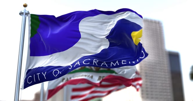 Sacramento city flag waving in the wind with California state and United States national flags blurred in background. Sacramento municipal flag