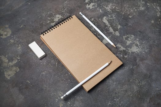 Blank kraft notebook, pencils and eraser on concrete background. Responsive design template.