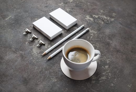 Photo of coffee cup and blank stationery set on concrete background. Objects for placing your design.