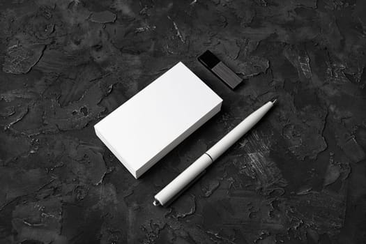 Photo of blank business cards, pen, usb flash drive on black plaster background. Responsive design template.