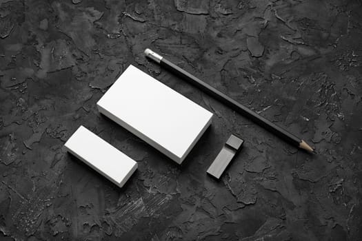 Photo of business cards, pencil, eraser and usb flash drive on black plaster background. Branding mock up.