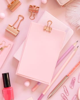 Paper with a clip and Pink school accessories on pastel pink, top view, mockup. Girly workplace with scissors, pencils, pen, paperclips, earrings and nail polish. Back to school concept