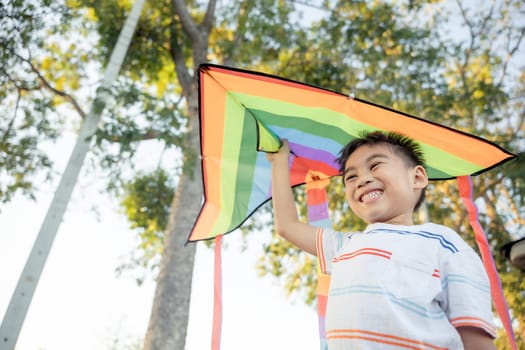 Asian happy children boy with a kite running to fly on in park at summer sunset outdoors