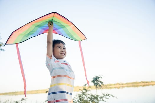 Asian happy children boy with a kite running to fly on in park at summer sunset outdoors