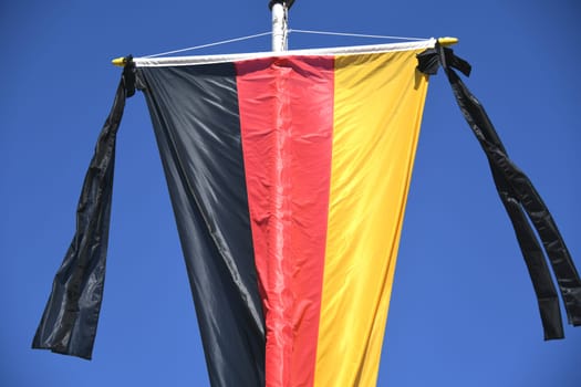 The national flag of the Federal Republic of Germany,black,red and gold,hangs on the flagpole. As a symbol of national mourning,the mourning ribbon is attached to the flag with two black ribbons.