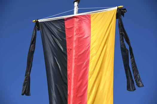 The national flag of the Federal Republic of Germany,black,red,gold,hangs on the flagpole. As a symbol of national mourning,the mourning ribbon is attached to the flag with two black ribbons.