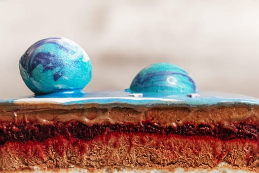 Blue mousse cake with blue chocolate balls in a section with a berry layer