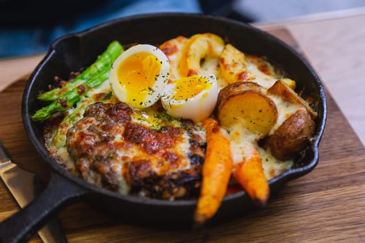 Fried pork with asparagus and egg in a small pan, served in a street cafe