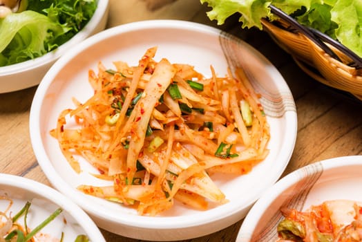 Spicy Kimchi. Korean pickle or Pickled radish vegetables and seasoning on bowl on wood table background, Japanese food