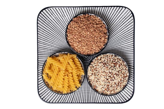 Vegetable food. Macro of a decorative plate with three bowls with buckwheat, noodles and quinoa isolated on a white background. Clipping path. Healthy eating. Top view.