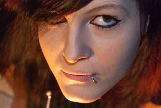 Young punk emo Girl with piercing, with red and black hair, looking at camera with serious facial expression, close-up