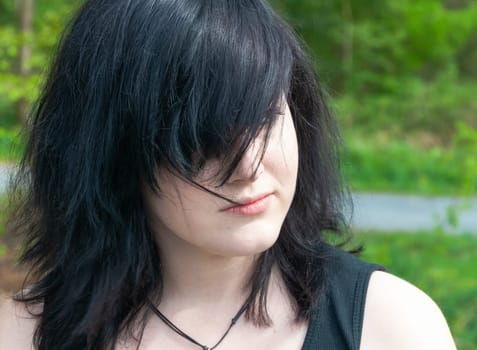 Gothic emo woman with black hair and black clothes, looking away, close-up