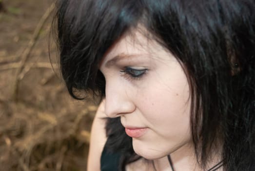 Punk emo girl, young adult with black hair and eyeliner, looking away, forest, close-up, horizontal