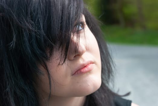 Punk emo girl, young adult with black hair and eyeliner,  looking up, outdoors, horizontal, close-up